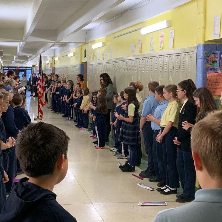 Children and adults standing in a hallway with an American flag