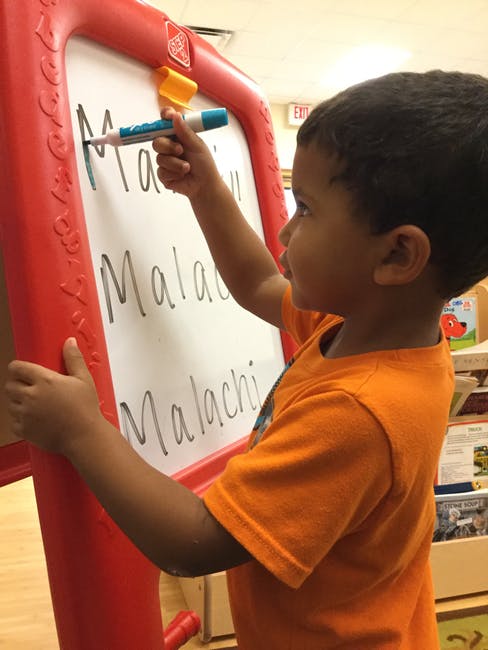 Child writing on a whiteboard with a marker