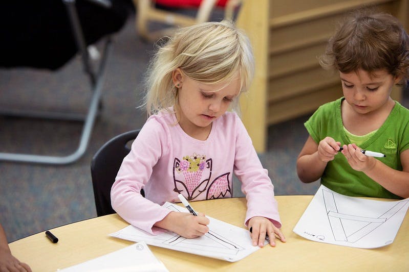 Two children drawing at a table