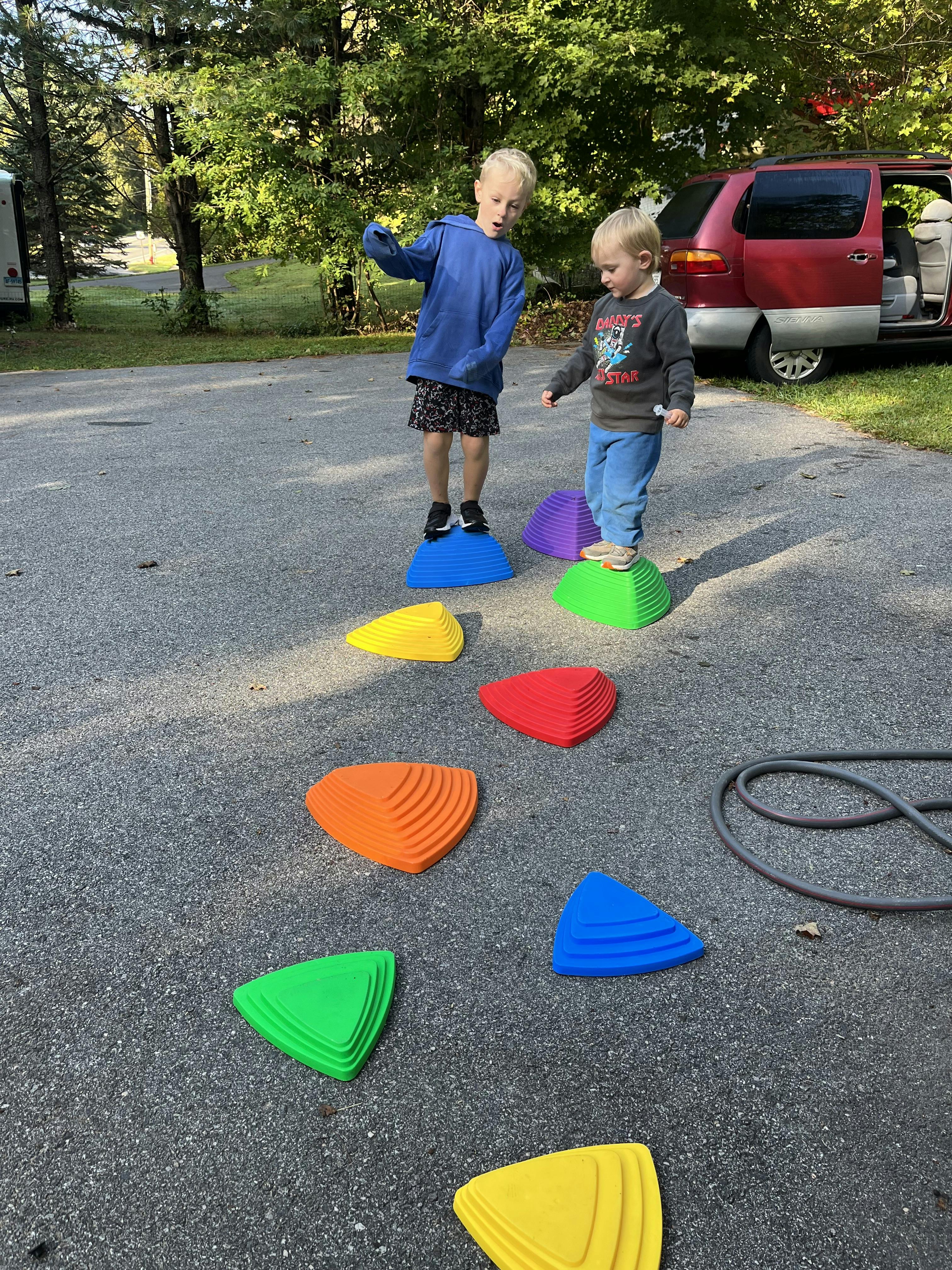 Two children playing on colorful stepping stones outdoors