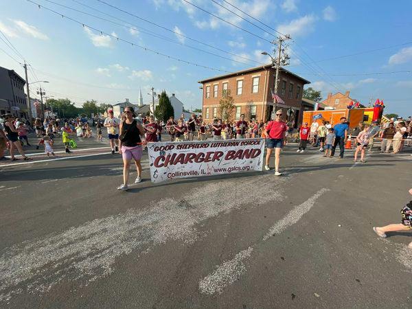 People carrying a banner for the Good Shepherd Lutheran School Charger Band