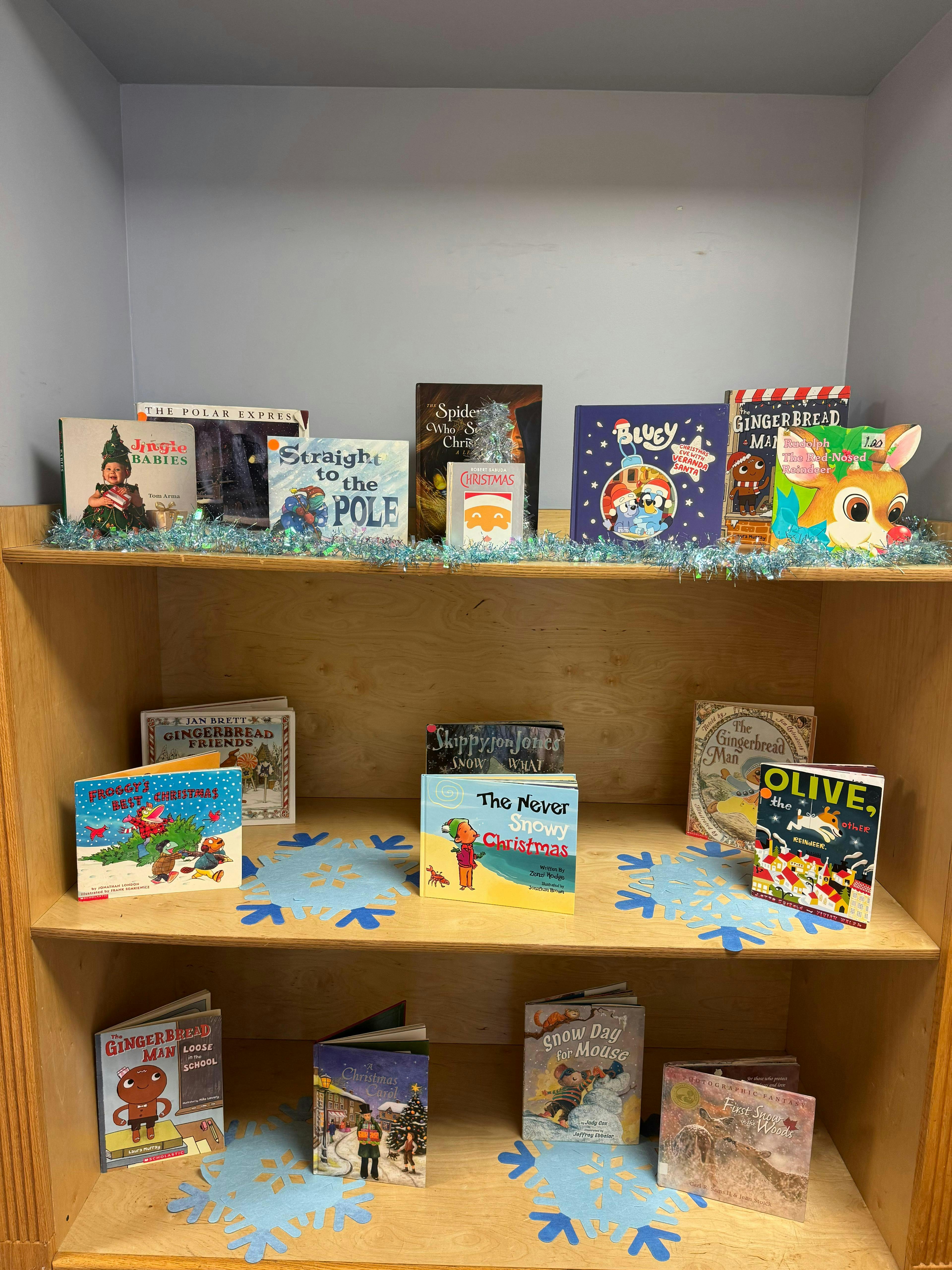 Children's Christmas books displayed on a wooden bookshelf