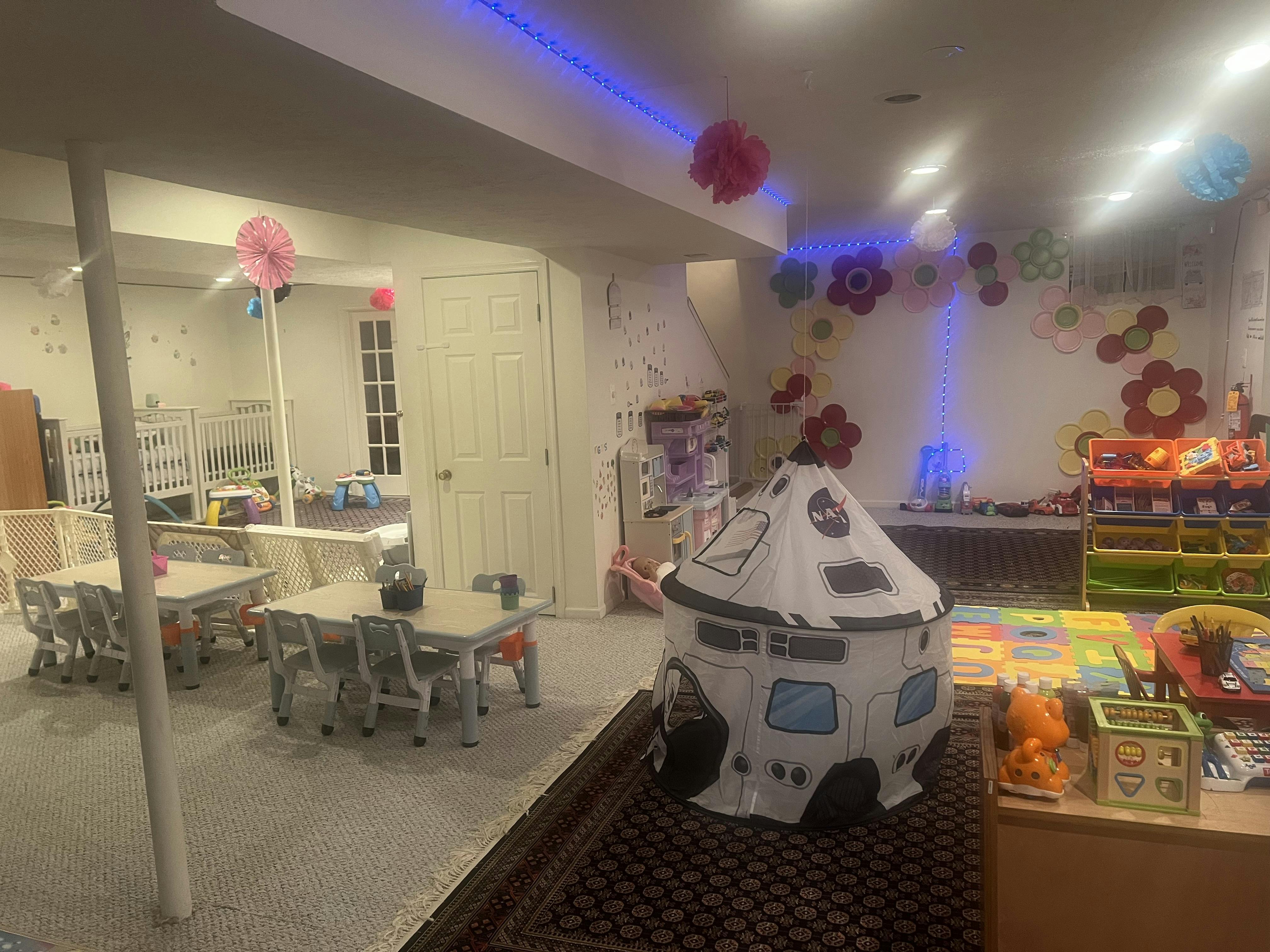 Playroom with small tables and chairs, a play tent, and toys