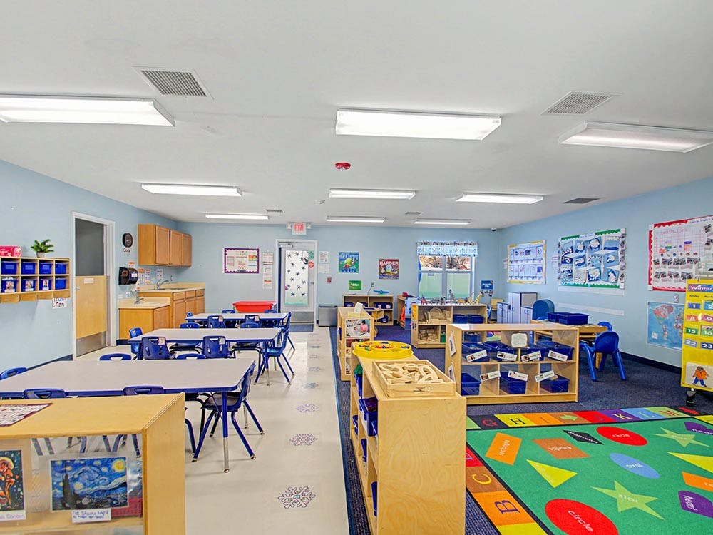 Empty colorful preschool classroom with small tables and chairs