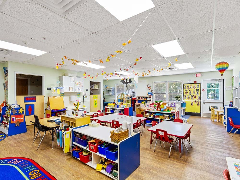 A colorful and brightly lit classroom with small tables, chairs, and toys