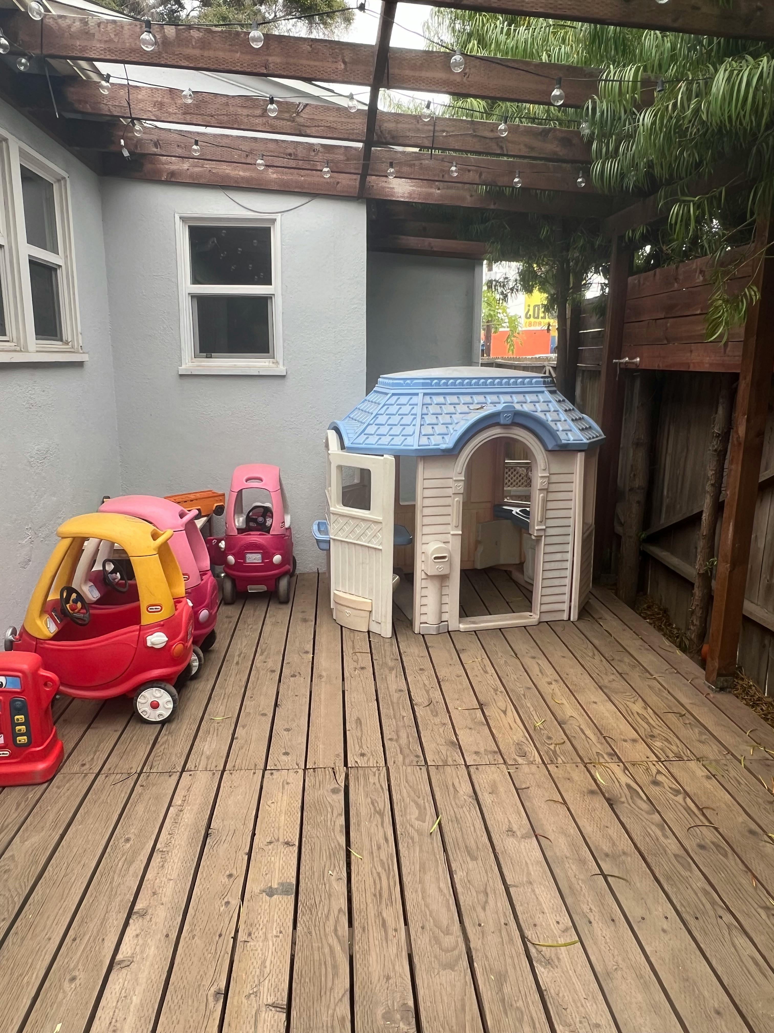 Toy cars and a playhouse on a wooden deck