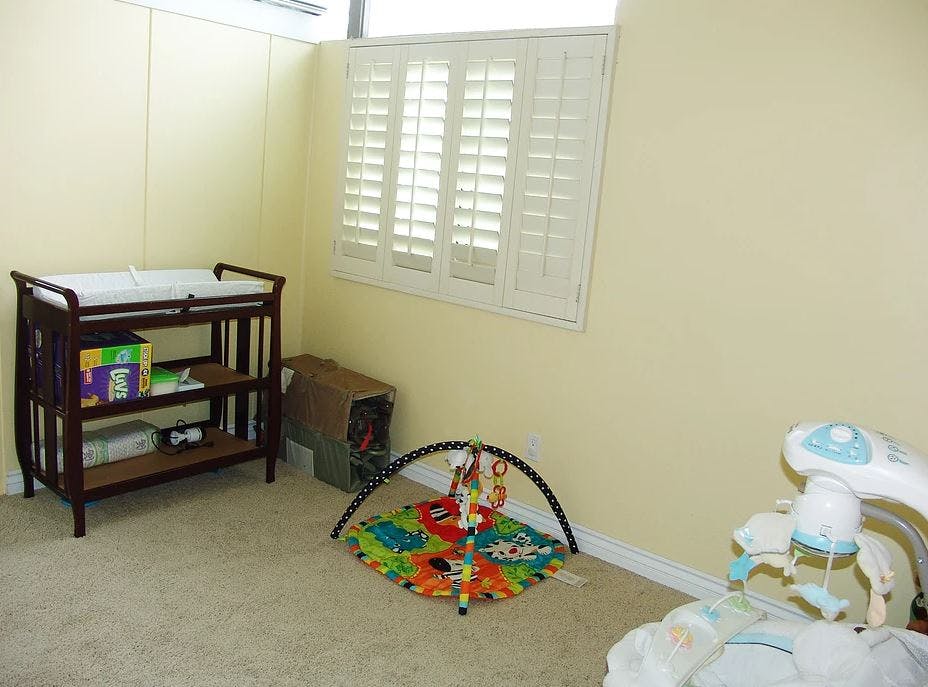 Nursery room with changing table, play mat, and baby swing