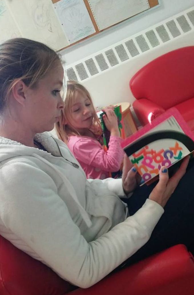 Person and child reading a book with colorful letters