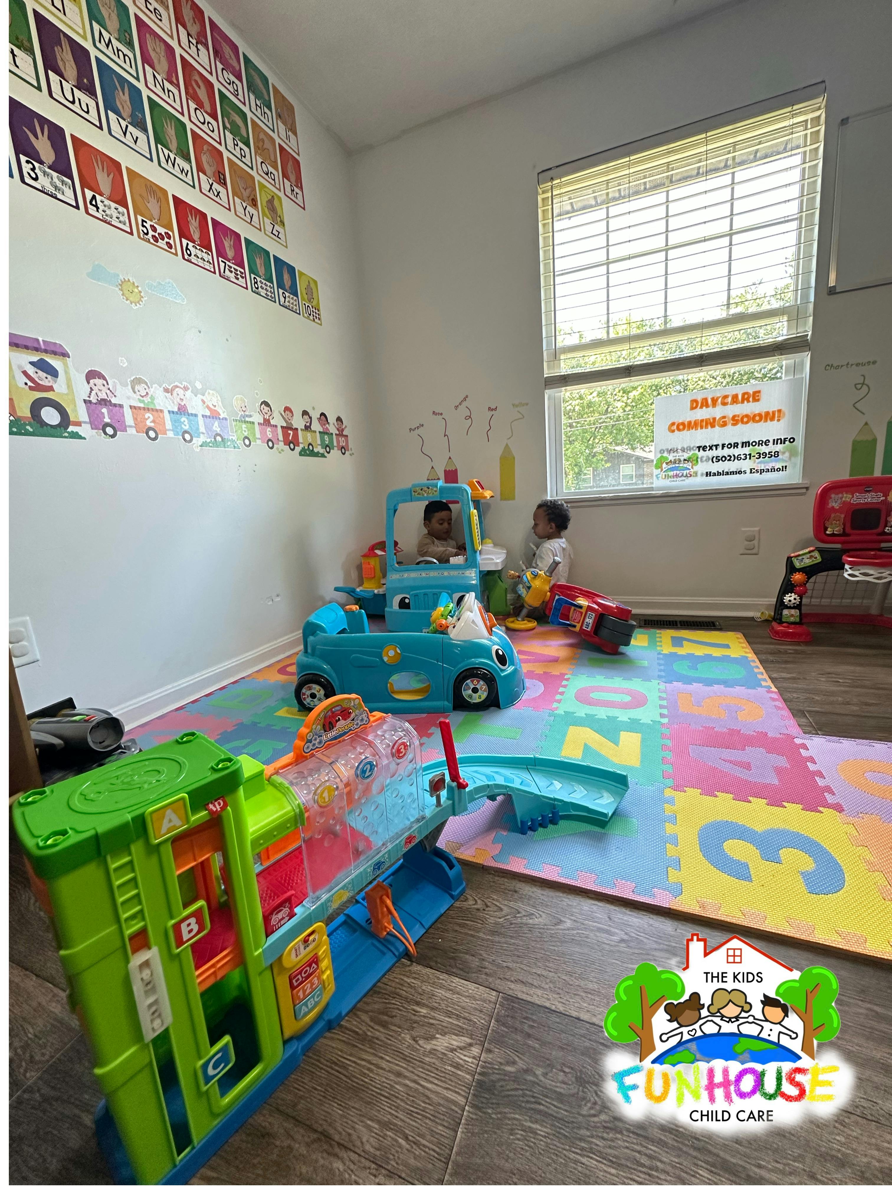 Two children playing with toy cars on a colorful number mat in a playroom