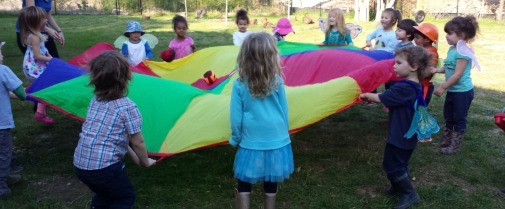 Children playing with a colorful parachute outdoors