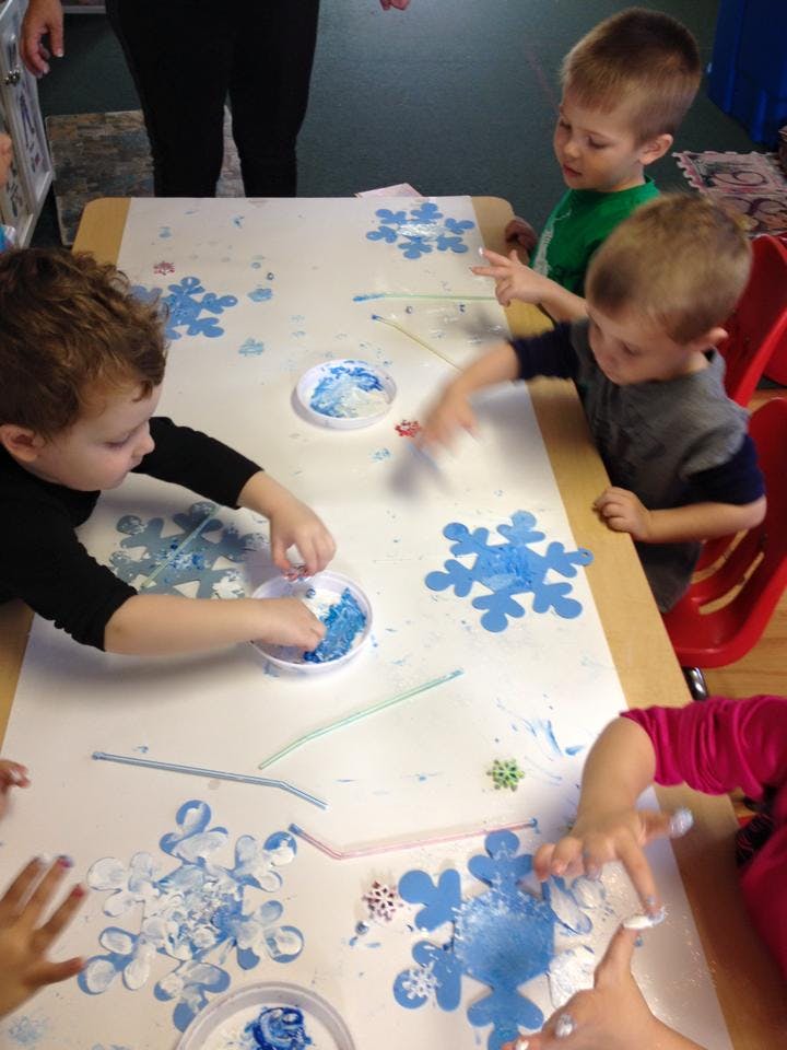 Children doing a snowflake craft at a table