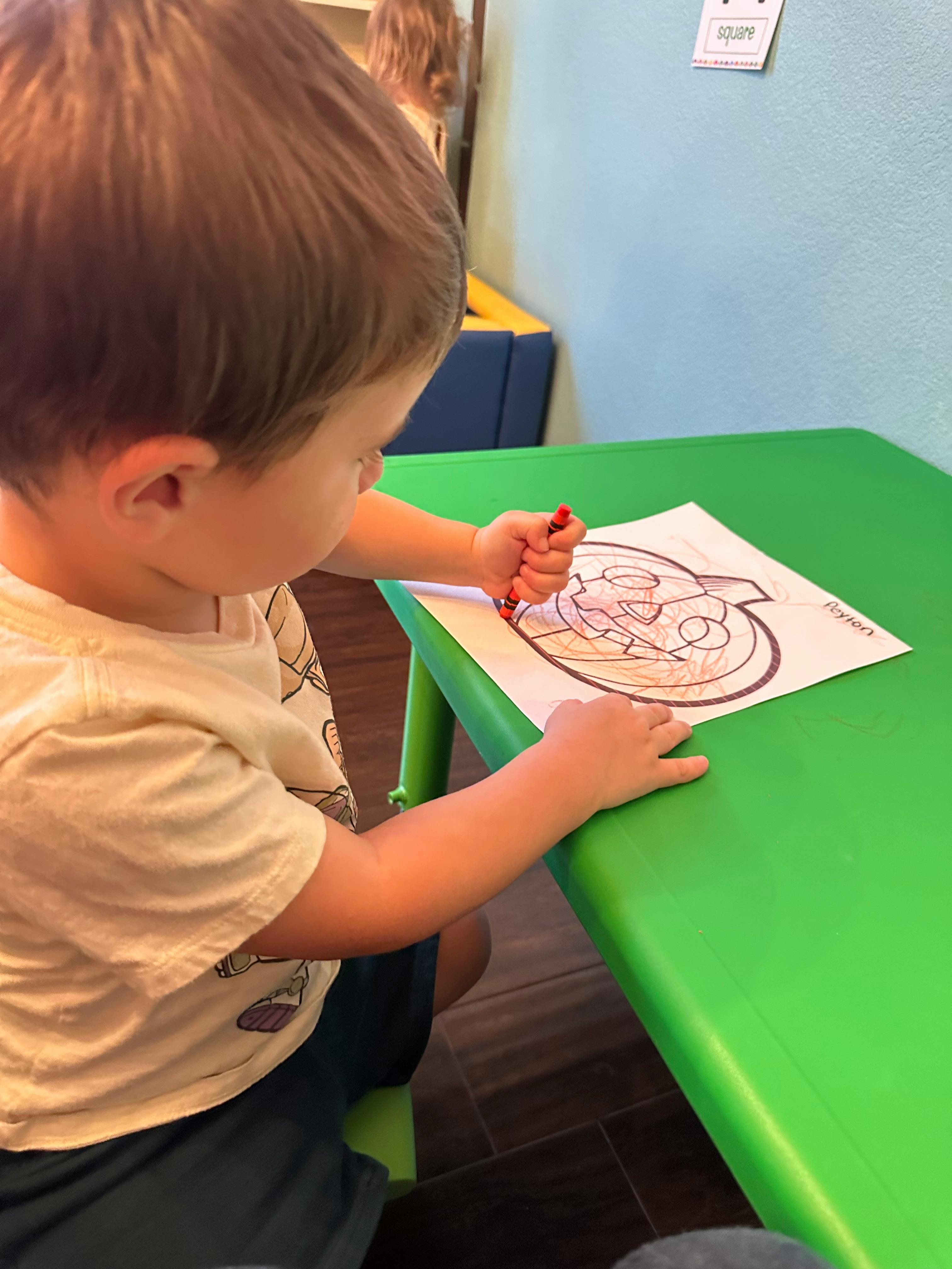 Child coloring a picture at a green table