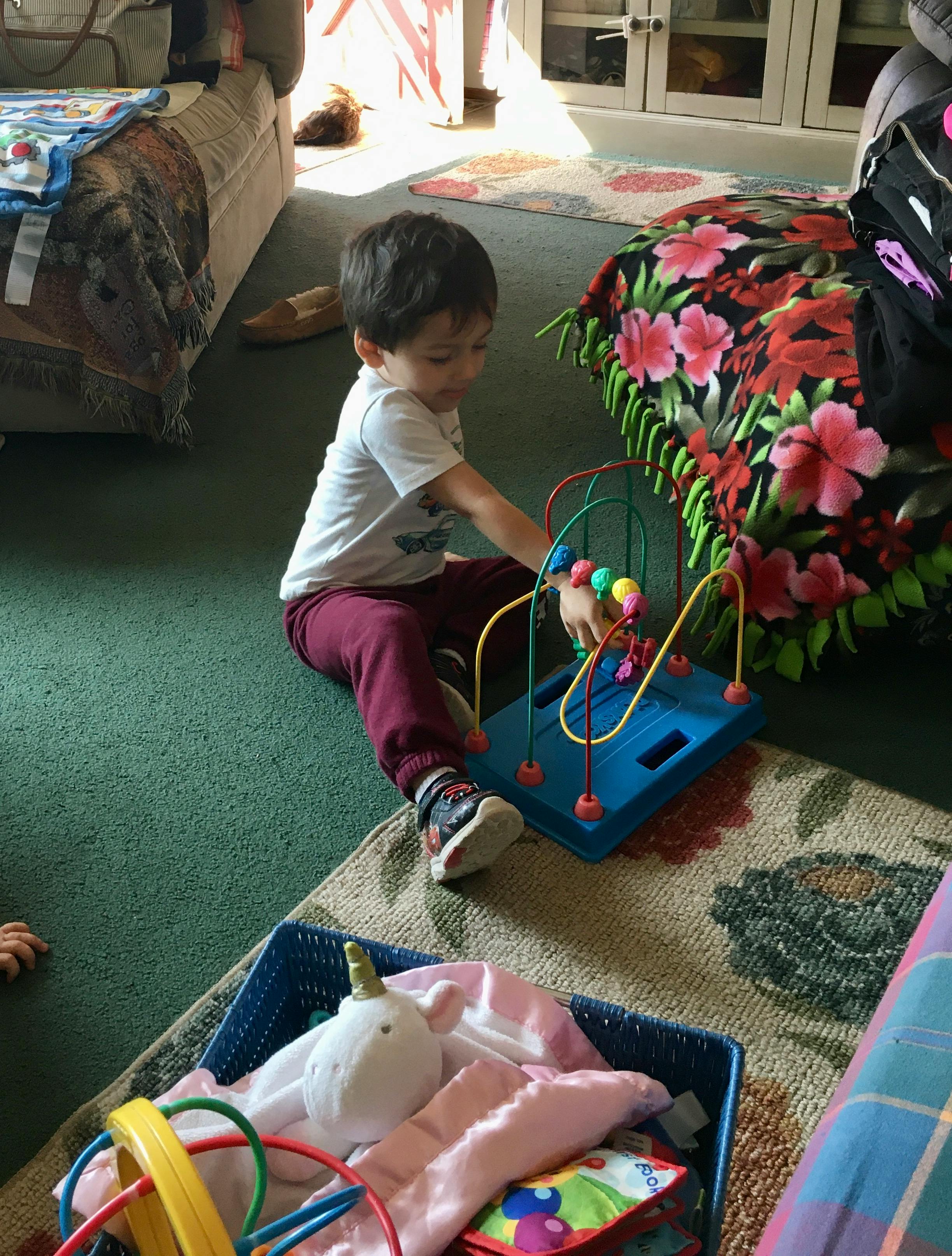 Child playing with a bead maze toy on the floor