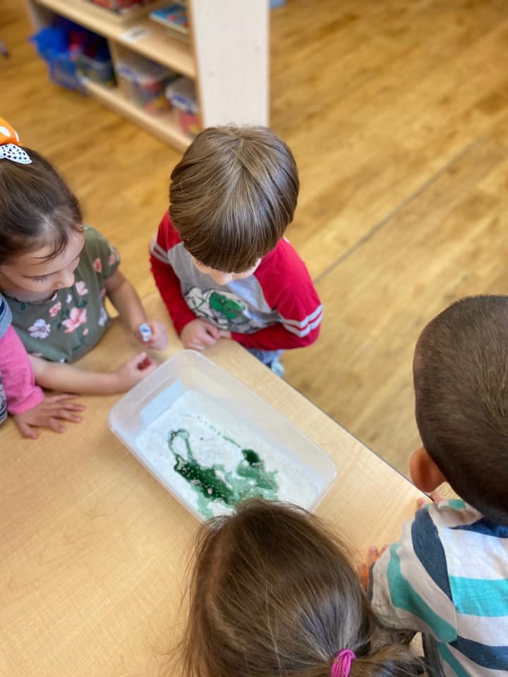 Children gathered around a container with green liquid