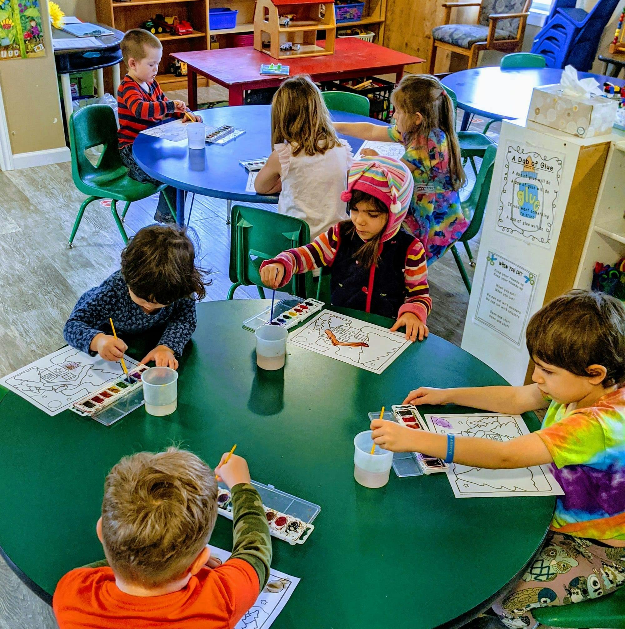 Children painting at tables in a classroom