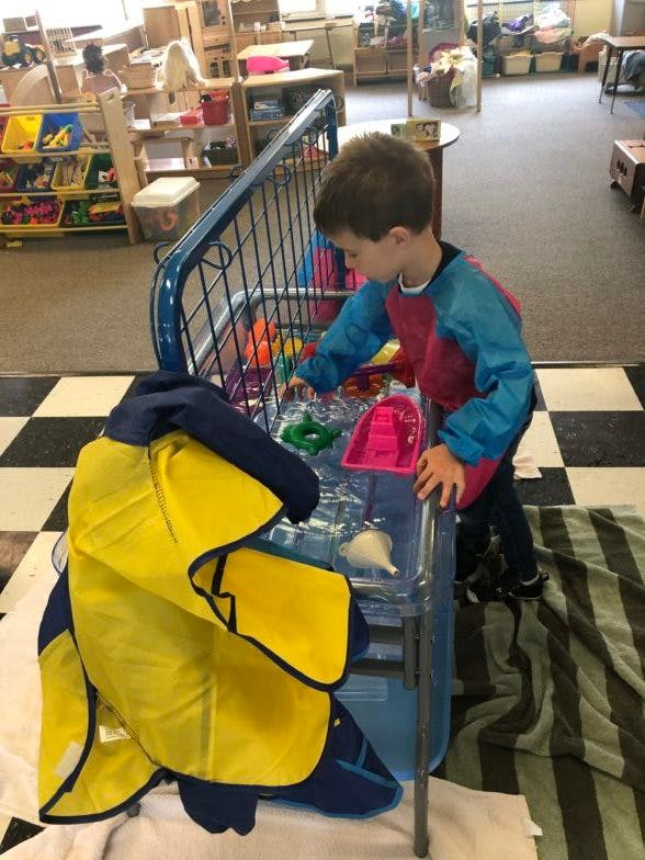 Child playing with toys in a water table