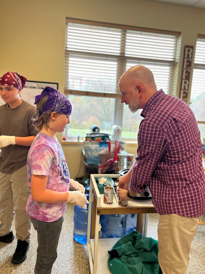 Two people and a child wearing bandanas and gloves preparing food