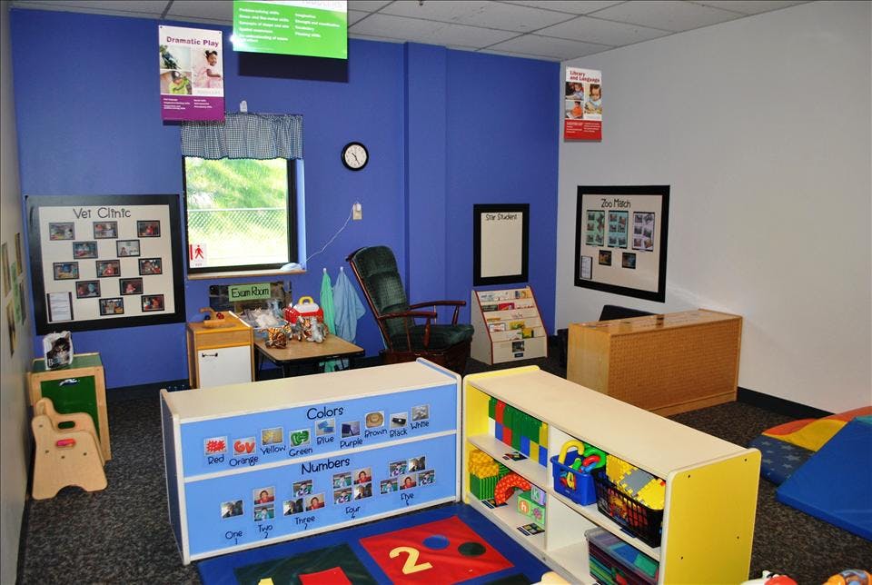 Classroom with blue walls, posters, a window, a rocking chair, and child-sized furniture