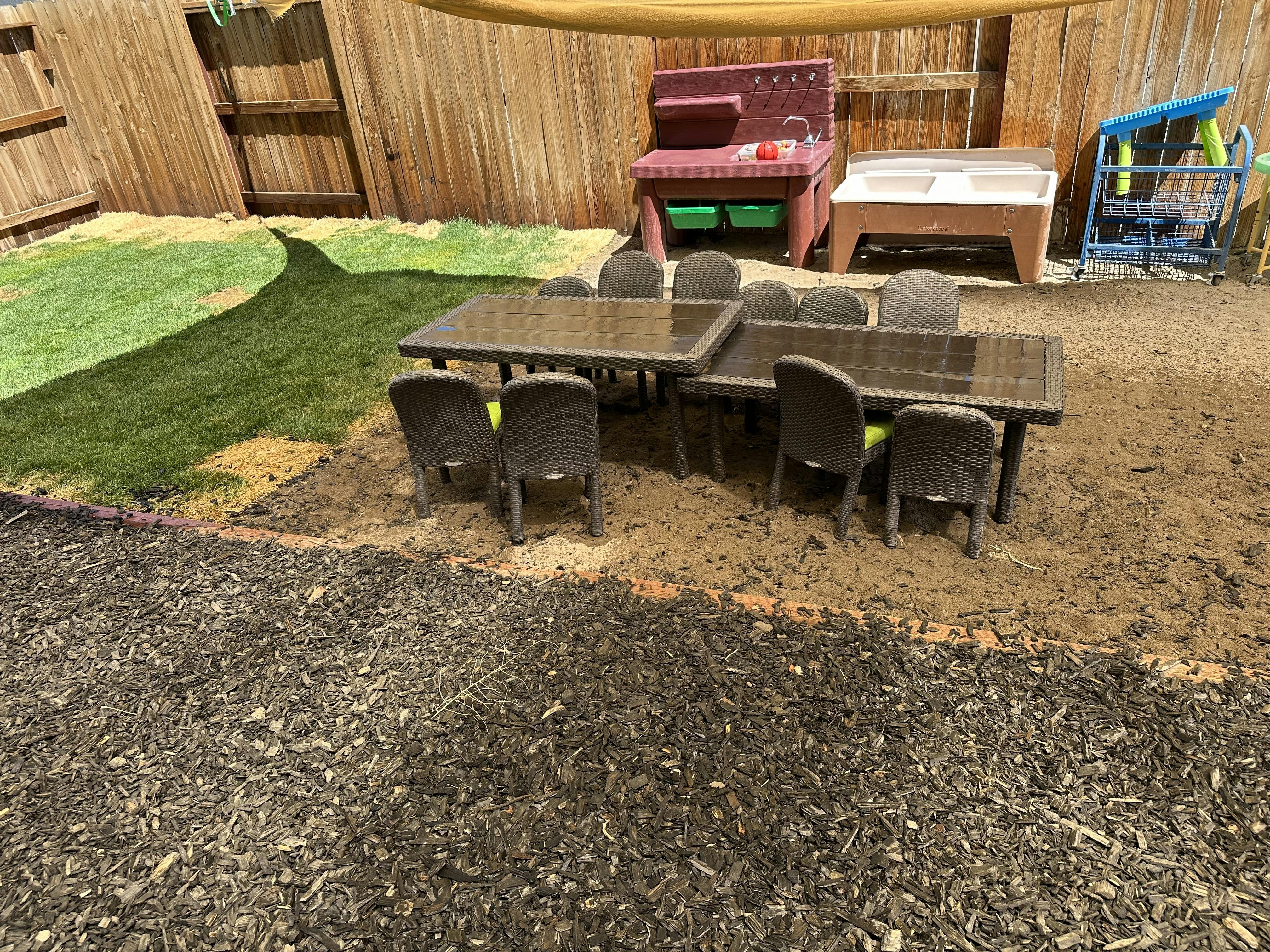 backyard patio area with two tables and chairs, a play sink, and a shopping cart