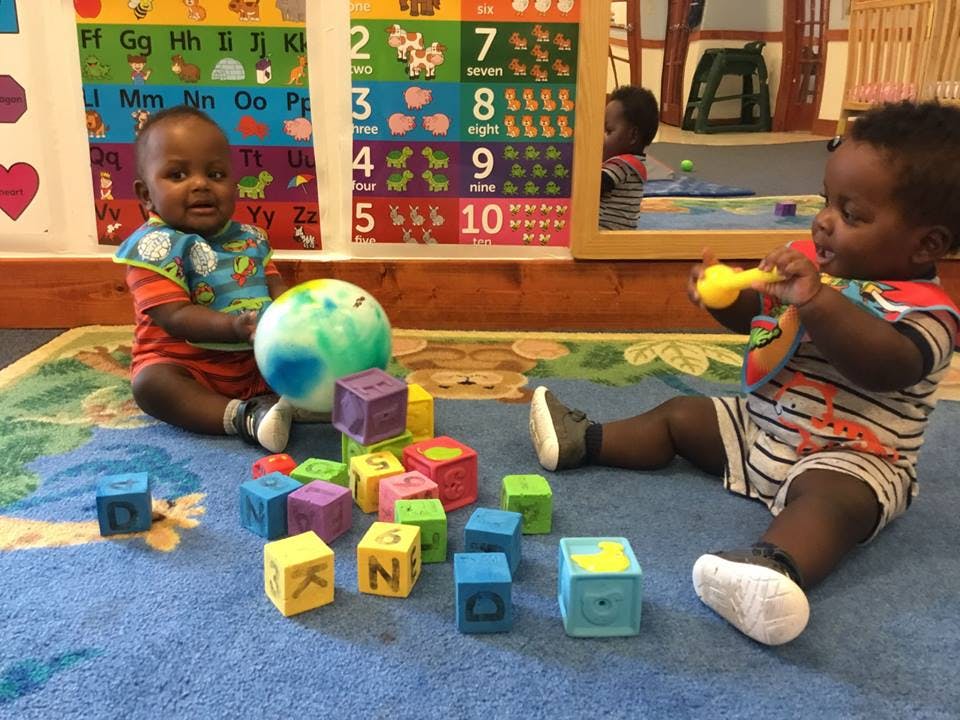 Two children playing with blocks and toys on a rug