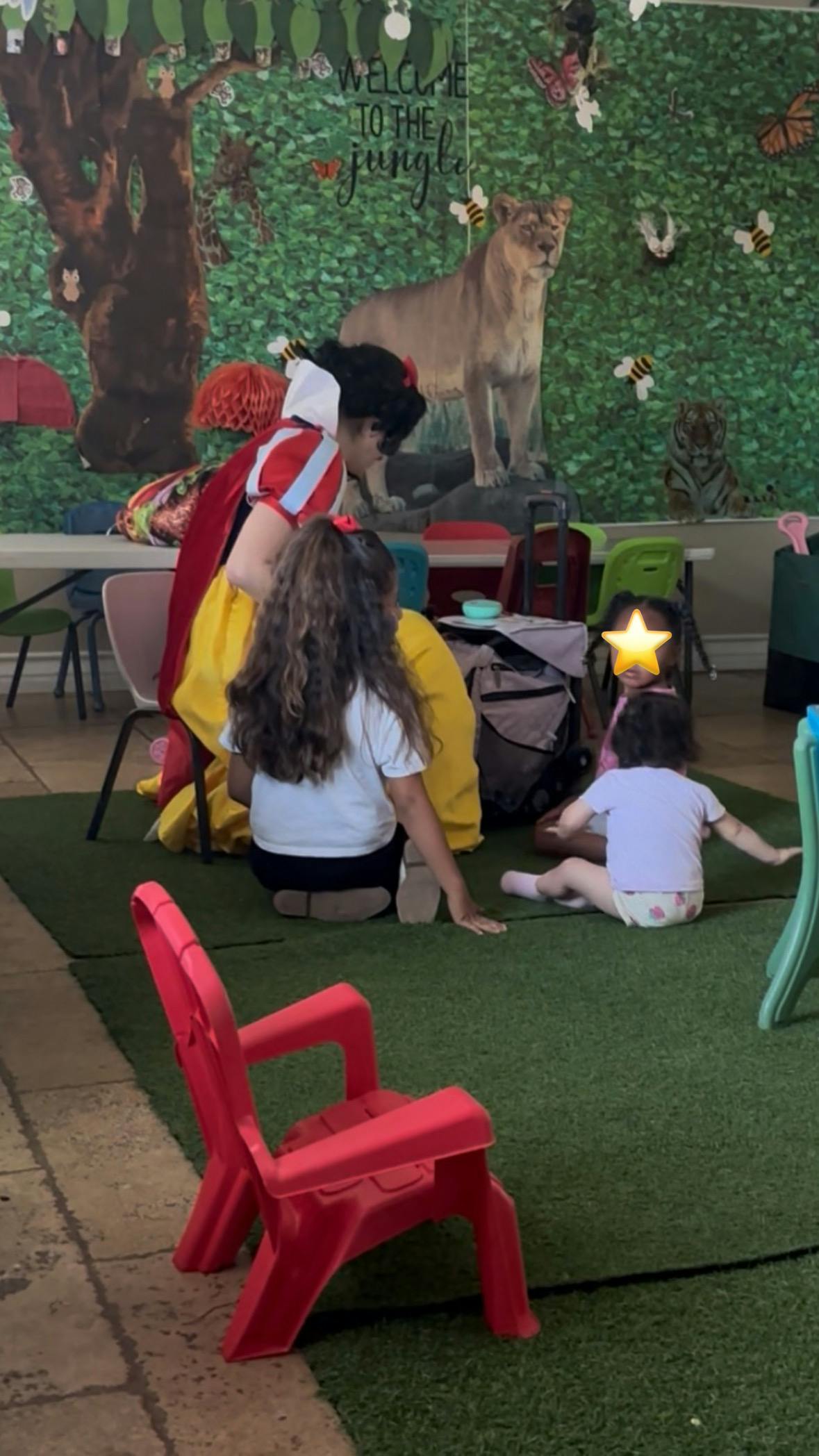 Person dressed as Snow White on floor with a child and two toddlers