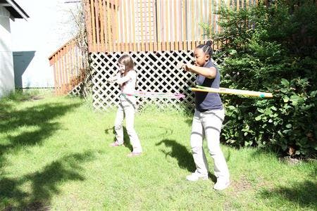 Two people playing with hula hoops in a grassy yard