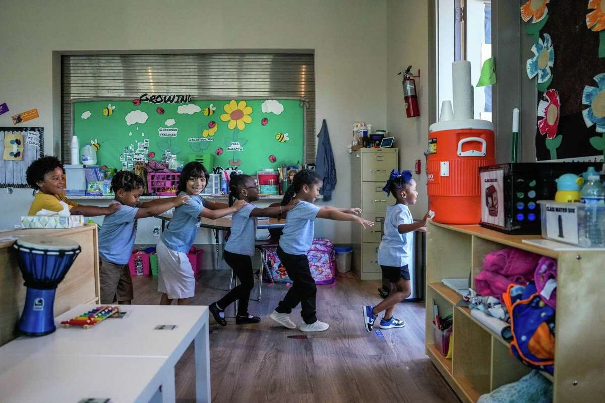 Children in a classroom holding hands in a line