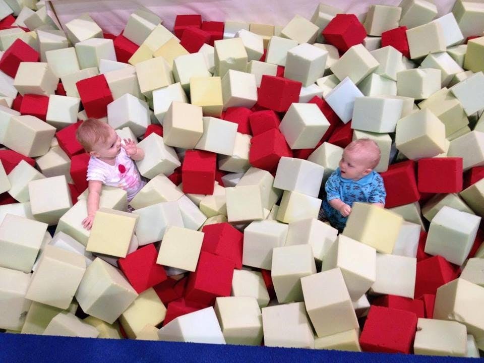Two children in a pit of foam blocks