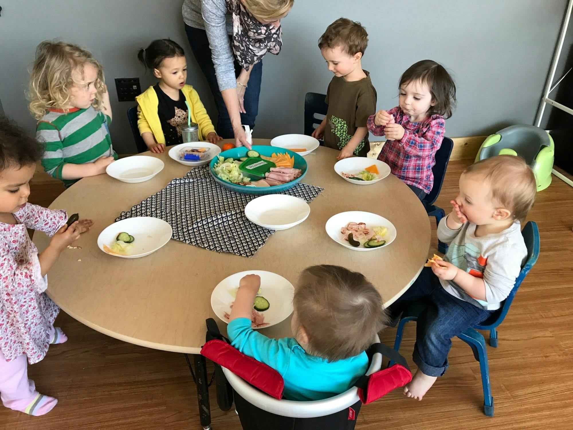 Adult serving food to children at a table
