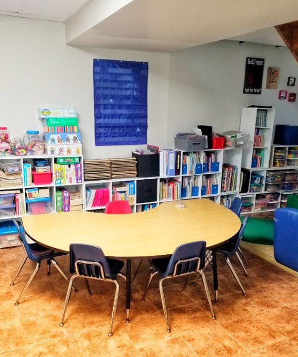 Classroom with a kidney-shaped table and chairs surrounded by bookshelves