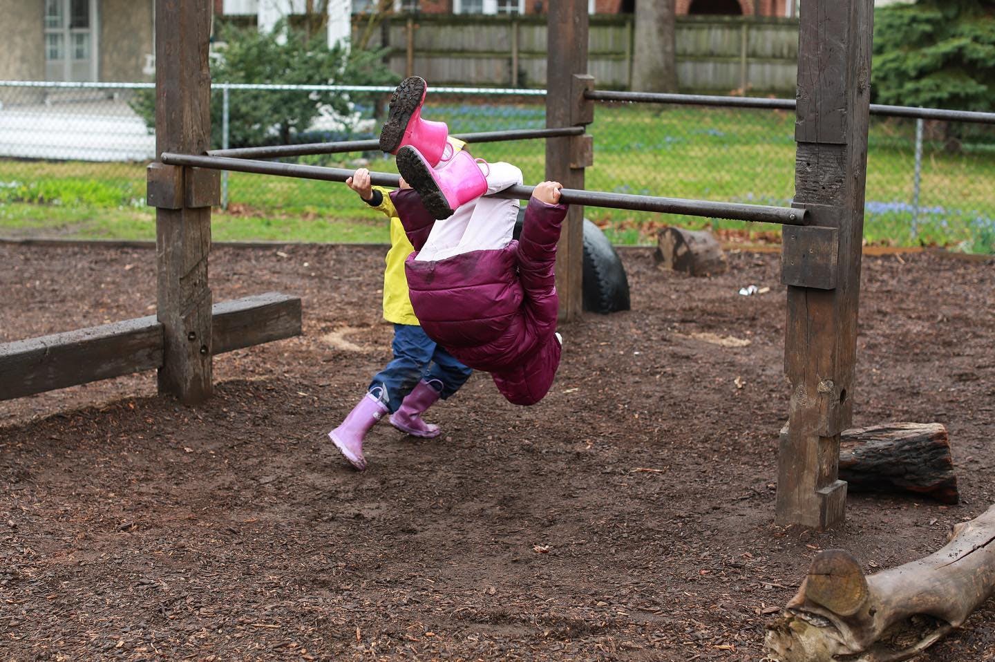 Child hanging upside down from a monkey bar