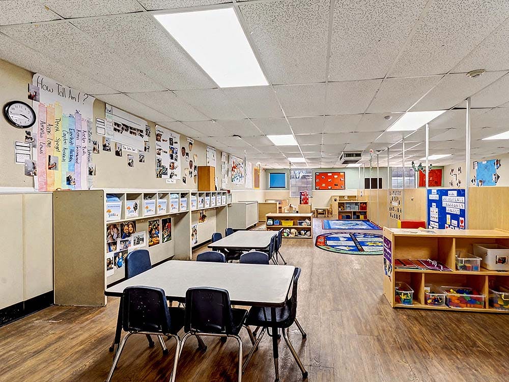Classroom with small tables and chairs, shelves, and decorations on walls