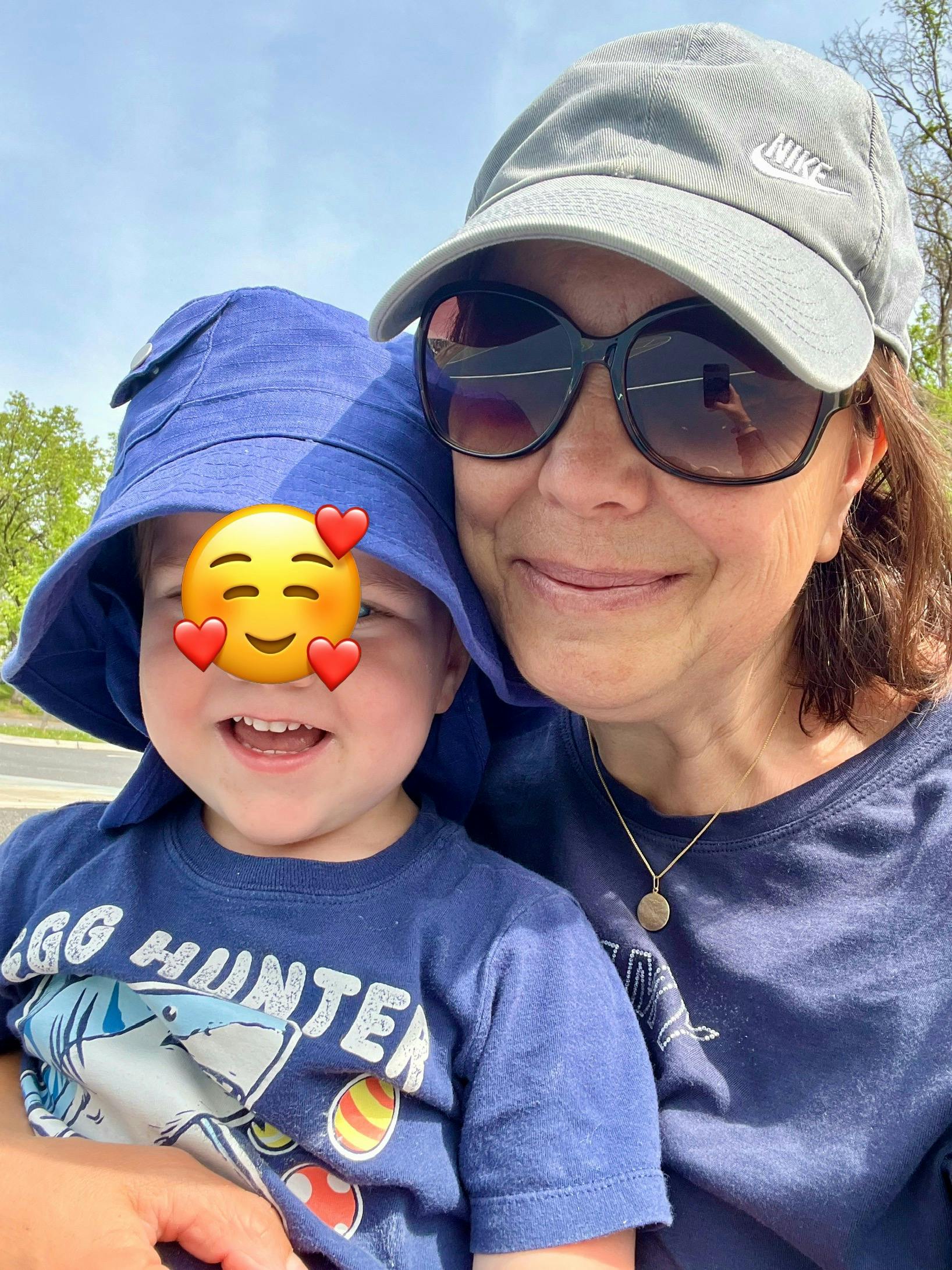 Person in sunglasses and cap with a child in a bucket hat