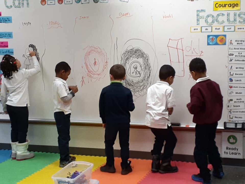 Children drawing on a whiteboard in a classroom