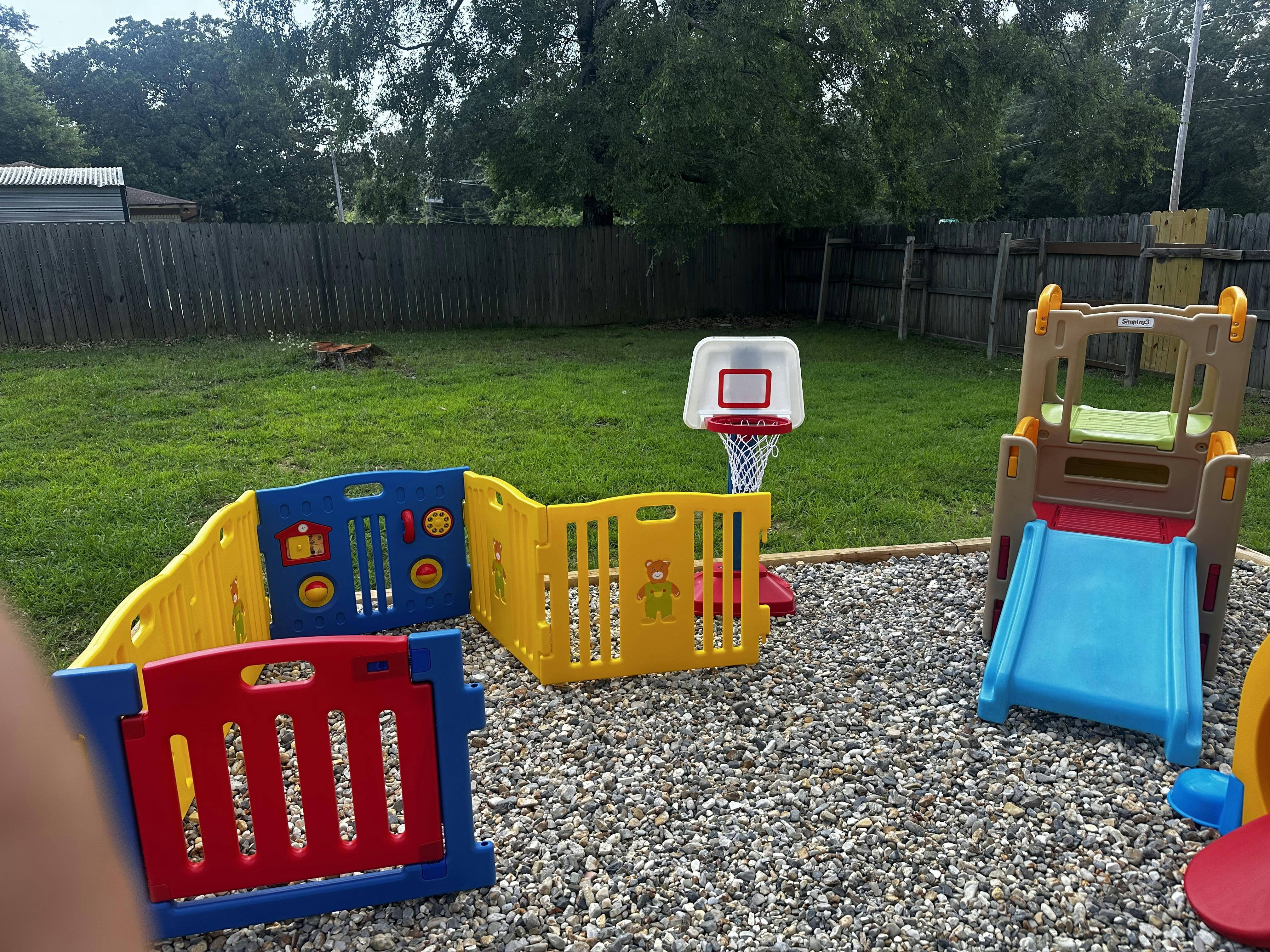 Play area with colorful plastic fence, basketball hoop, and slide