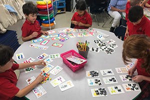 Children playing a game with cards and counters at a table