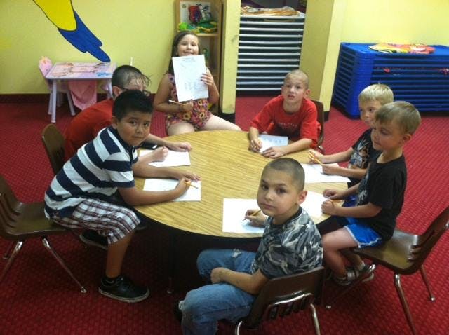 Children sitting around a table with papers and pencils