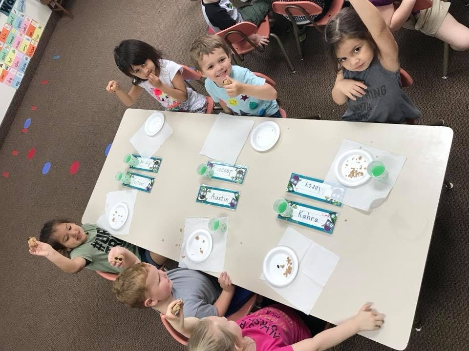 Children sitting around a table with plates and name tags