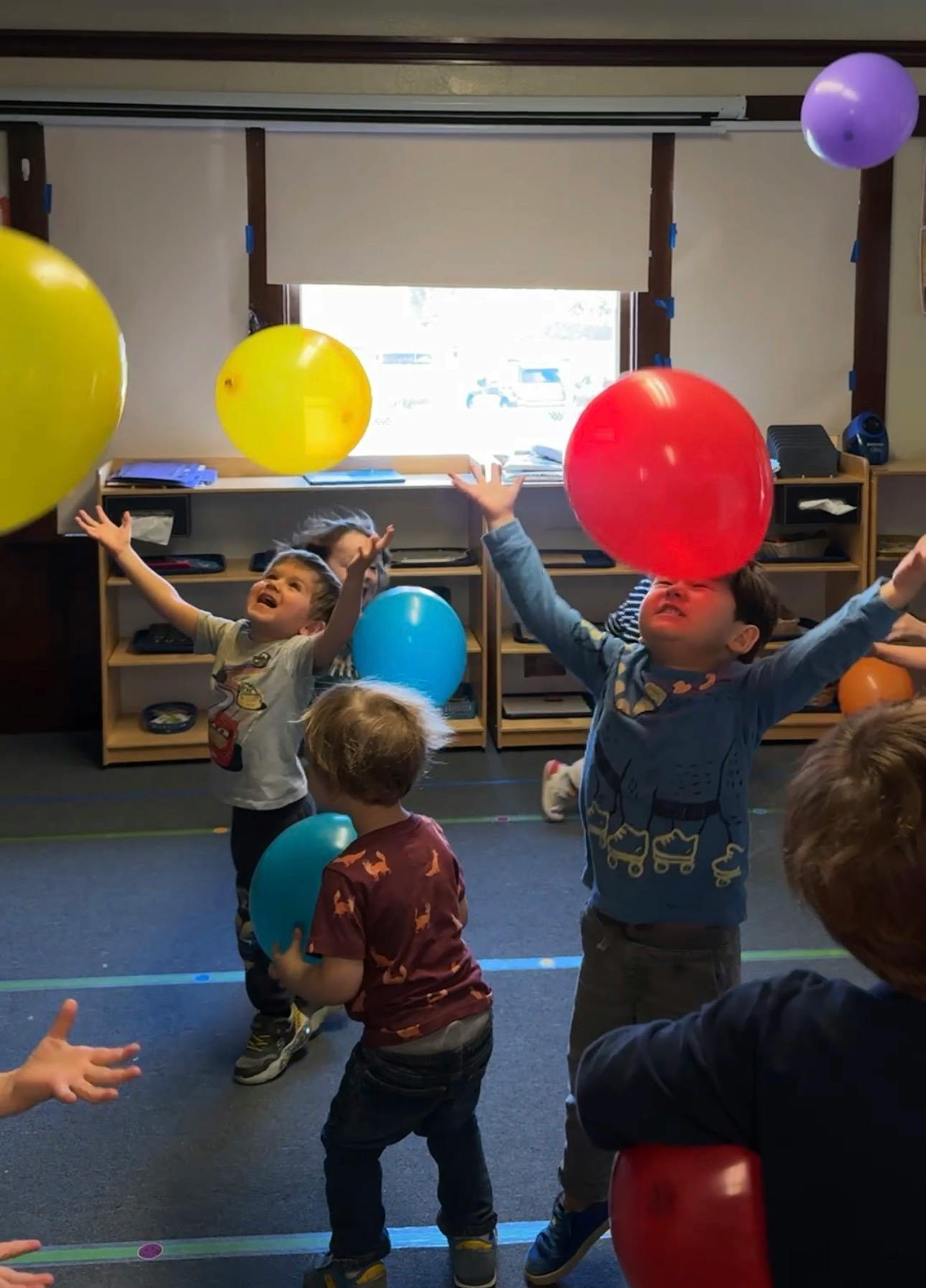 Children playing with balloons in a classroom