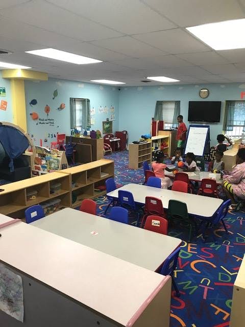 Children and adults in a classroom with tables and chairs