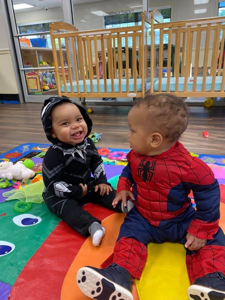 Two children in costumes sitting on a colorful mat
