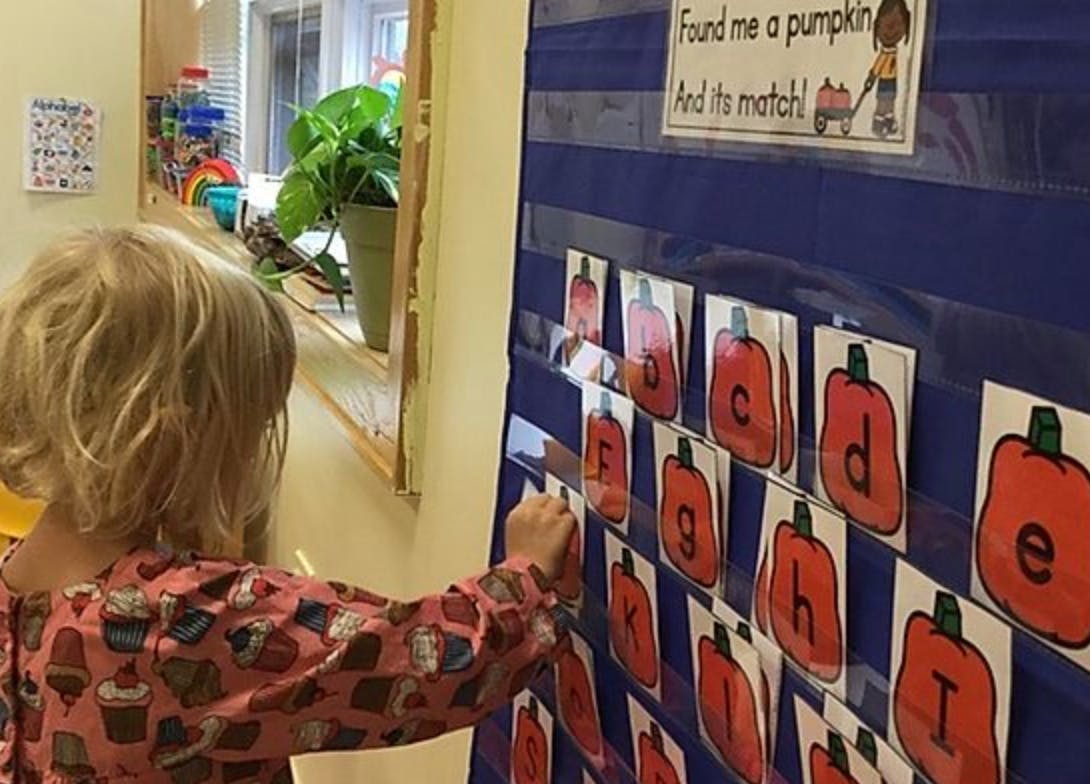 Child placing a letter card on a blue display board