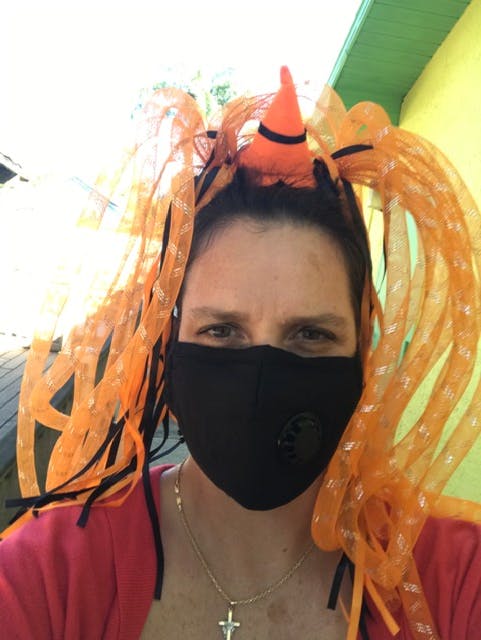 Person wearing a black face mask and an orange novelty headband