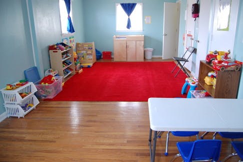 Room with red rug, hardwood floor, and children's furniture