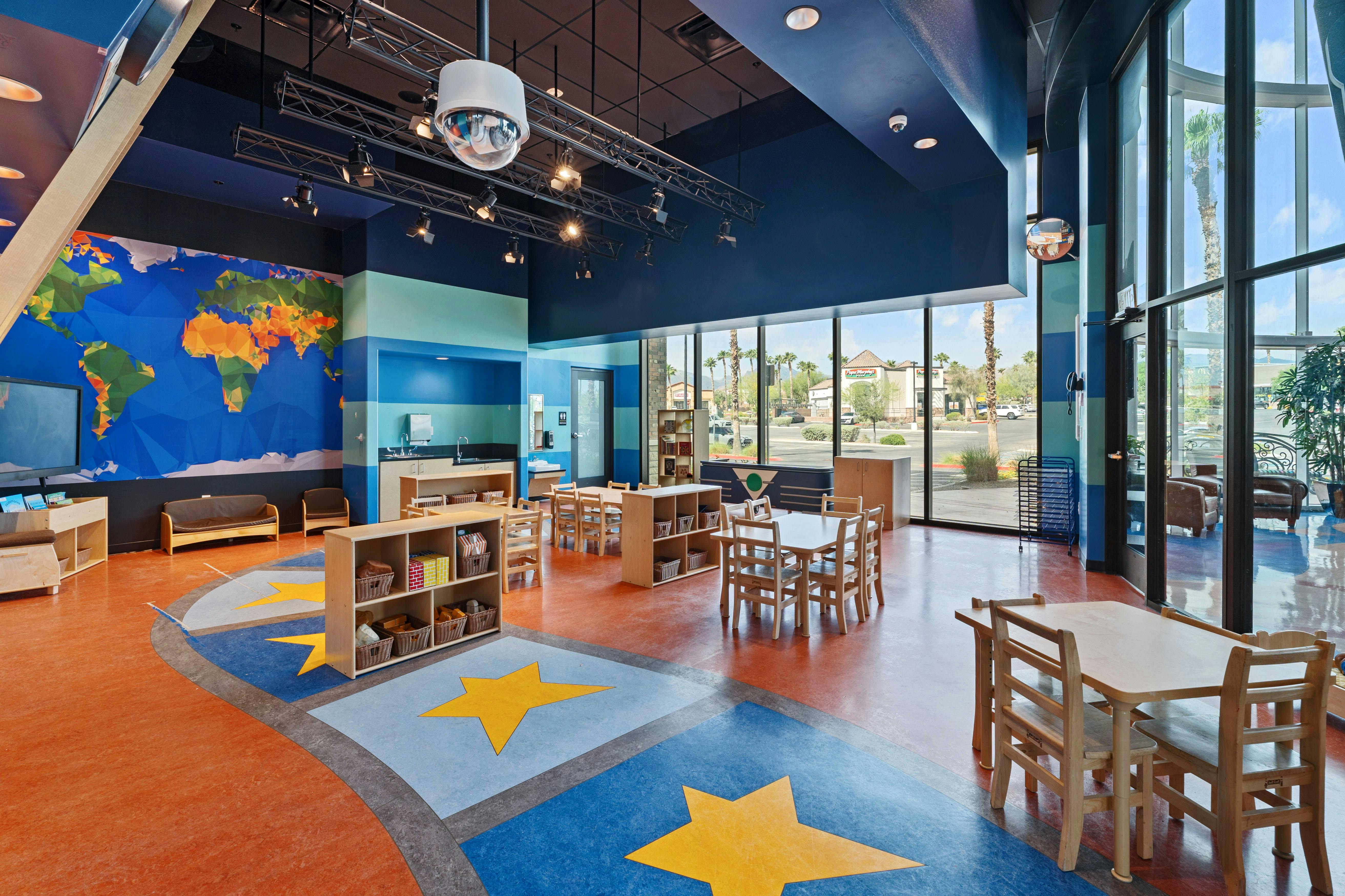 Children's classroom with small tables and chairs, and a world map mural