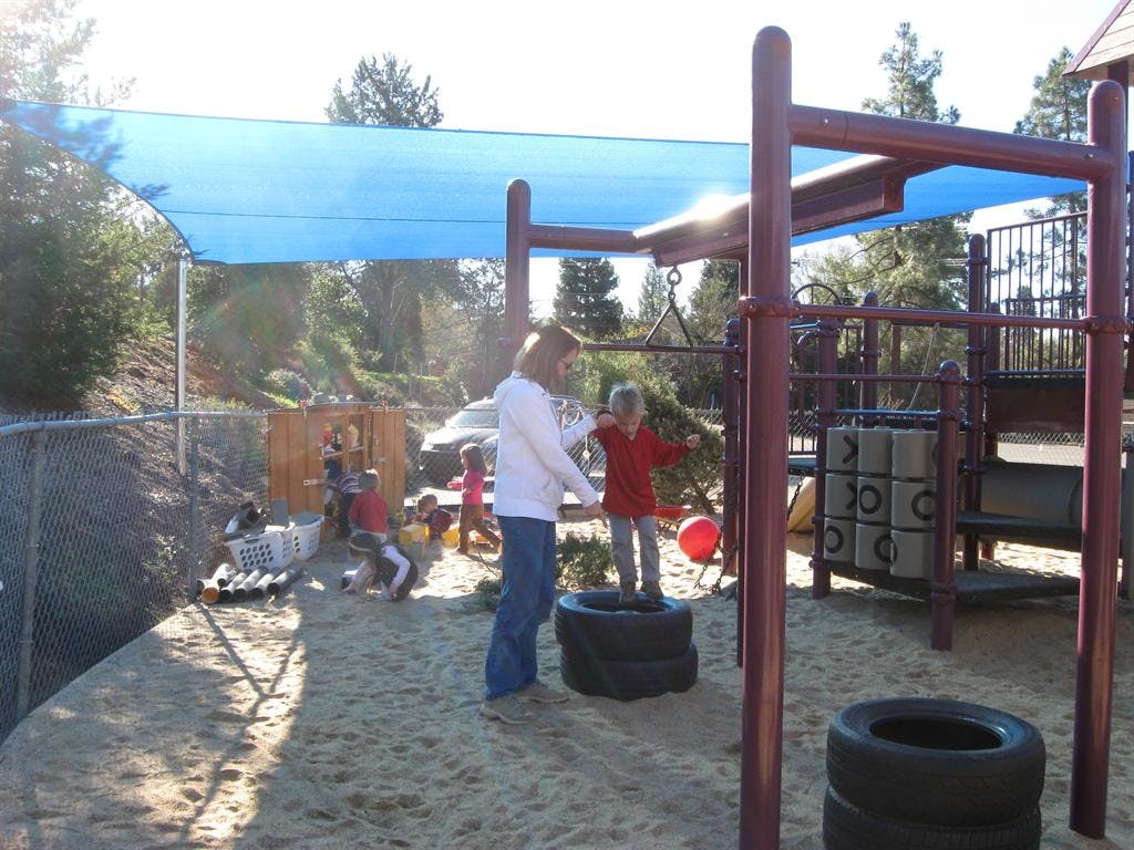 Adult and child playing in a sandbox with tires and playground equipment
