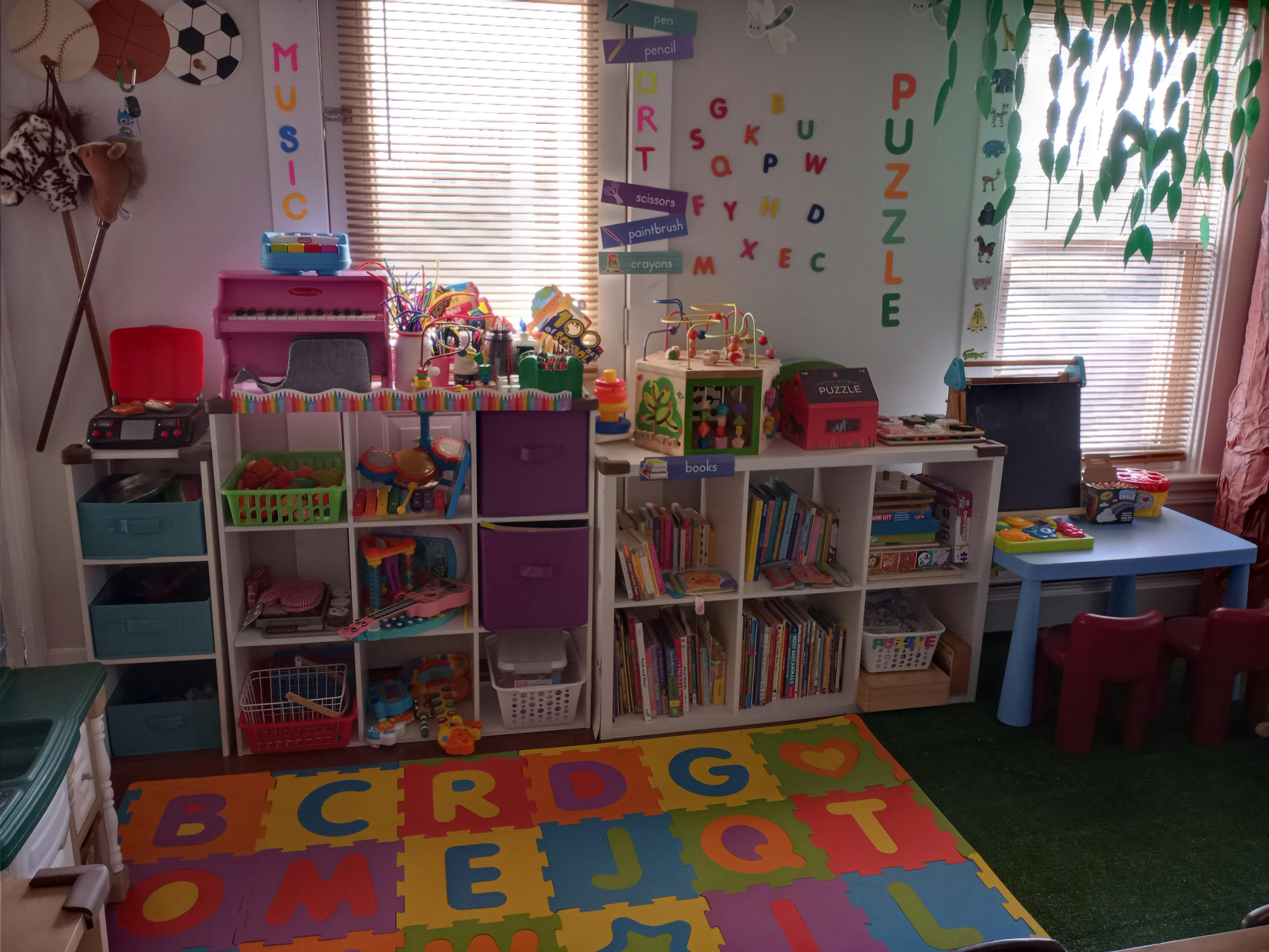 Playroom with shelves of toys and books, alphabet rug, and small table