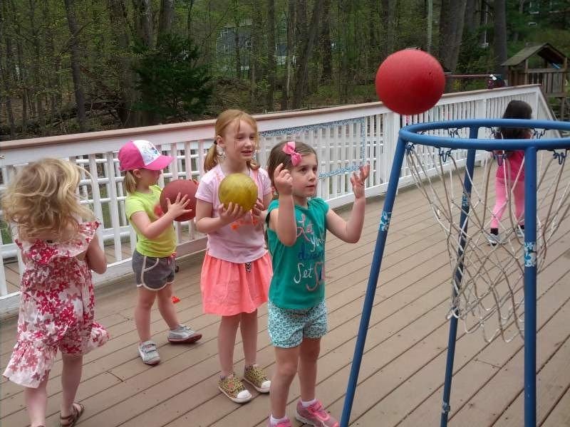 Children playing with balls and a basketball hoop on a deck