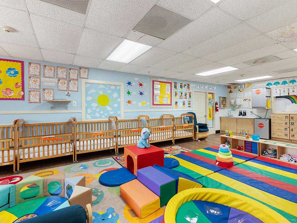 Cribs and colorful play mats in a bright daycare room