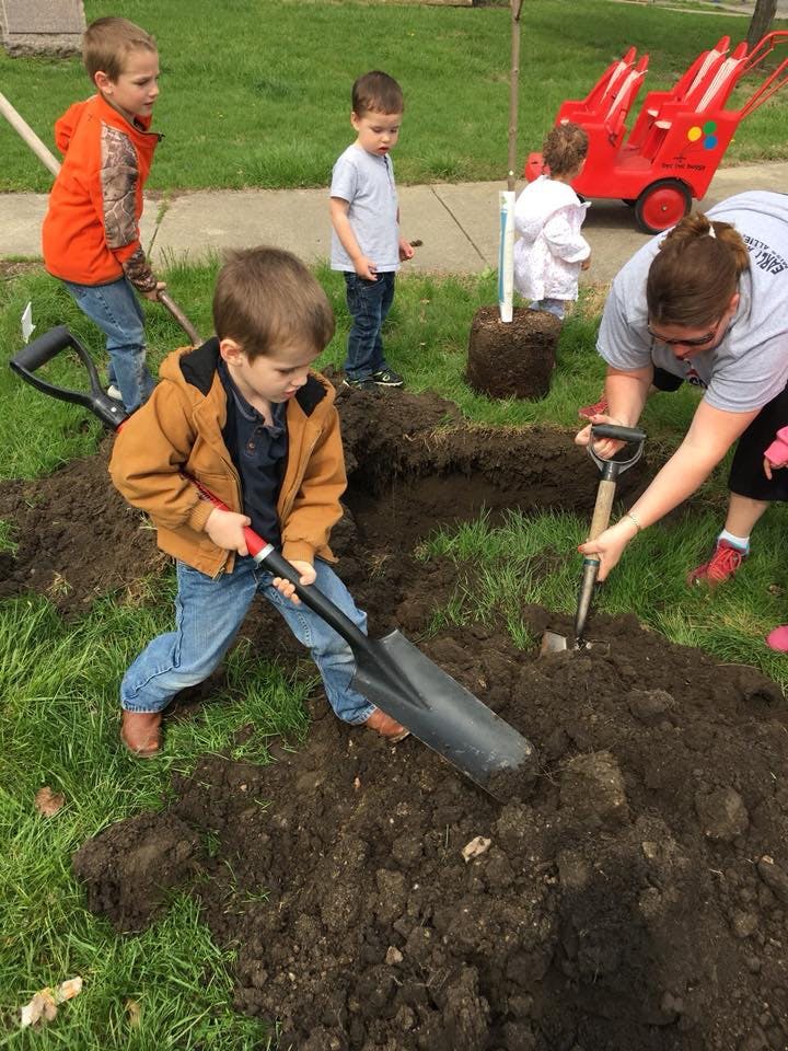 Adult and children digging in dirt with shovels